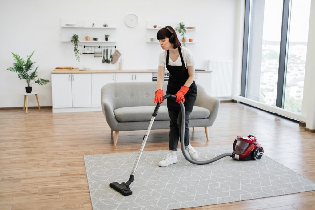 Cleaning service employee listens to music while cleaning spacious apartment.