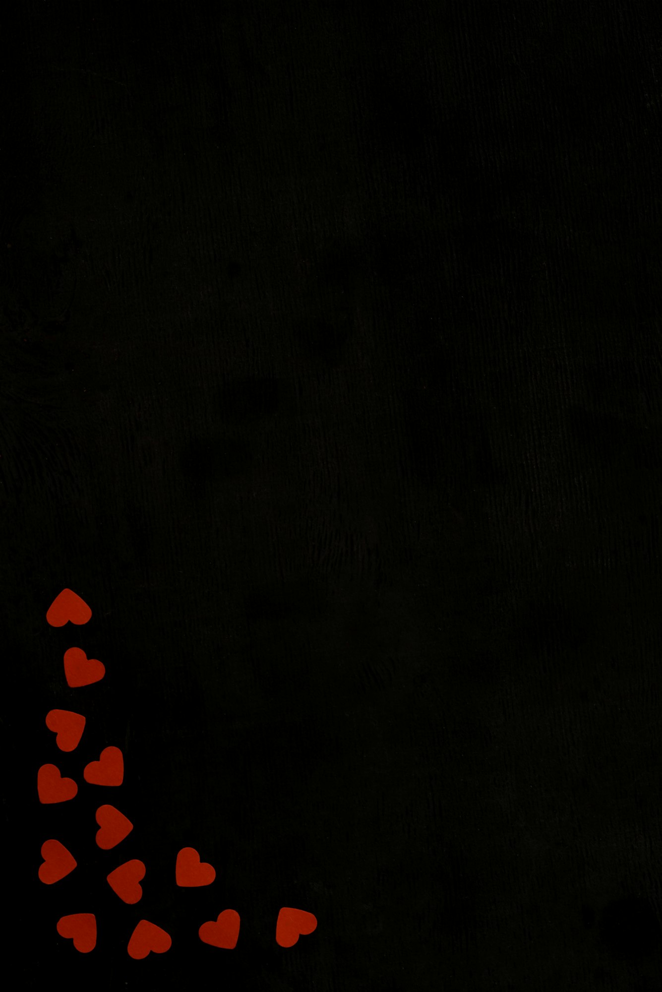 top view of red heart shaped confetti isolated on black